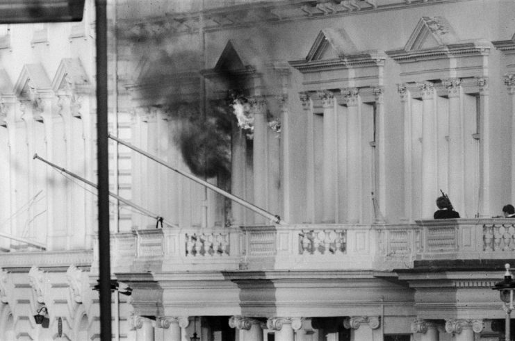 The SAS retook the embassy and freed the hostages, two SO19 officers stand on the balcony of the building adjacent to the Embassy, after SAS soldiers threw thunderflashes through the window to stun the hostages and terrorists inside.