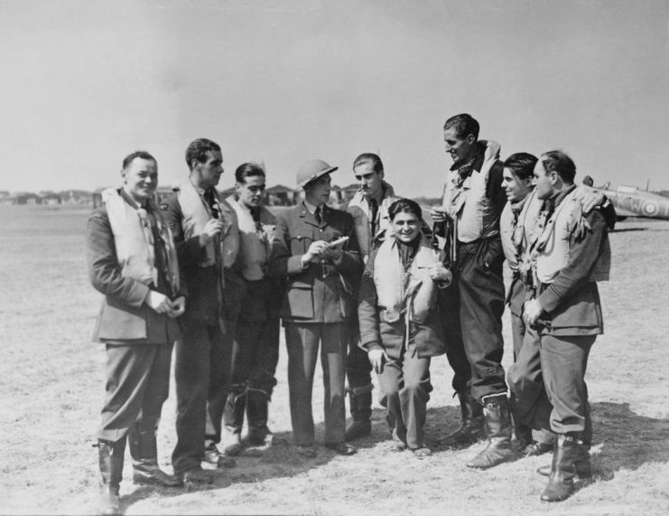 An Intelligence Officer (wearing helmet, centre) listens to the reports of fighter pilots of No 501 (County of Gloucester) Squadron, Royal Auxiliary Air Force, after a sortie during the Battle of Britain, at RAF Hawkinge, near Folkstone, Kent, 15th August 1940. The pilots are (left to right): Stefan Witorzenc, Hugh Adams, John Gibson, Paul Farnes (1918 – 2020), Antoni Gowacki, Bob Dafforn, Kenneth Lee and George Stoney. Sgt Antoni Głowacki is also notable for shooting down five German aircraft on 24th August 1940 during the Battle of Britain, becoming one of only four pilots who gained “ace-in-a-day” status during that battle. (Photo by Central Press/Hulton Archive/Getty Images)
