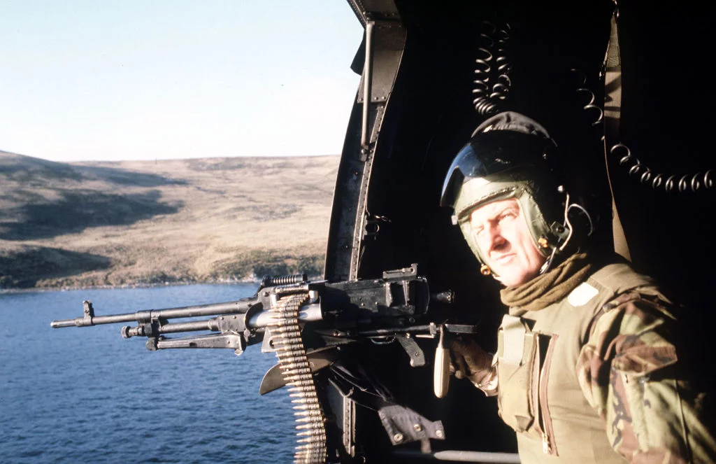 A crewman mans a General Purpose machine gun mounted in the hatchway of a helicopter on patrol over San Carlos Water during the Falklands conflict. (Photo by PA Images via Getty Images)
