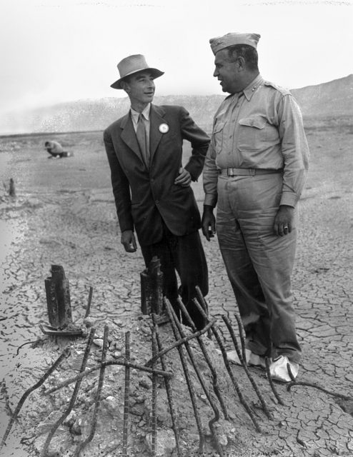 Oppenheimer and Groves at the remains of the Trinity test in September 1945, two months after the test blast and just after the end of World War II. The white overshoes prevented fallout from sticking to the soles of their shoes