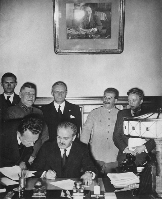Soviet Prime Minister Vyacheslav Molotov signs the Molotov–Ribbentrop Pact. Behind him stand (left) Foreign Minister Joachim von Ribbentrop of Germany and (right) Joseph Stalin. The non-aggression pact had a secret protocol attached in which arrangements were made for a partition of Poland’s territory.