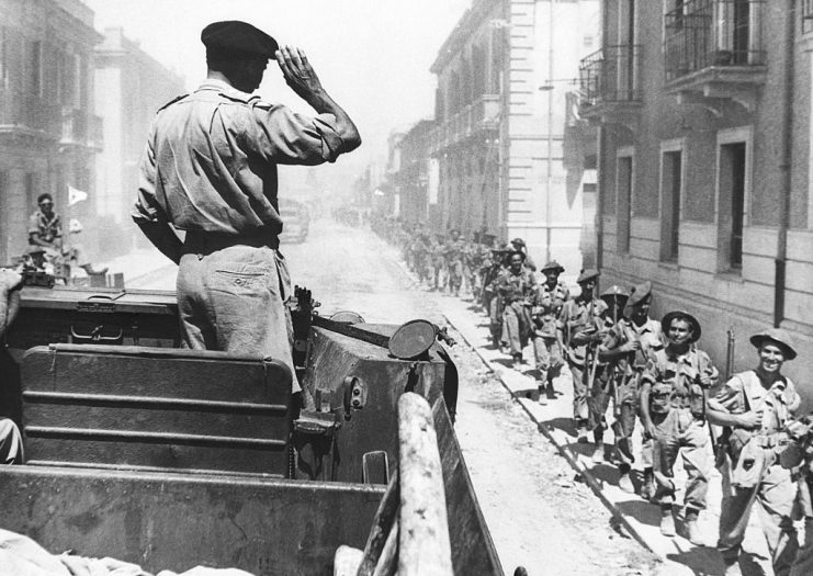 (Original Caption) 9/20/43-Reggio, Italy: Their smiling leader, General Sir Bernard L. Montgomery, greets men of the British Eighth Army as they march, single file, through the narrow streets of Reggio in the early stages of the allied invasion of the Italian mainland. This an original of the radiophoto previously serviced.