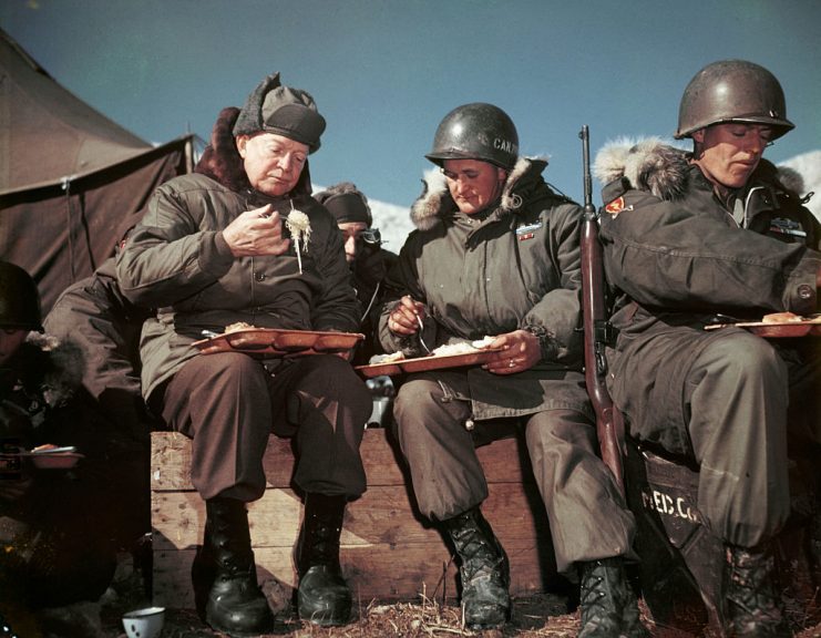On a visit to the front lines, President Eisenhower eats with American soldiers