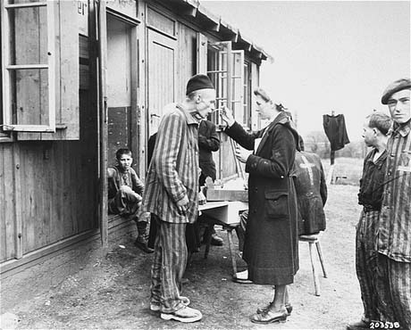 A sick Polish survivor in the Hannover-Ahlem concentration camp receives medicine from a German Red Cross worker, April 1945