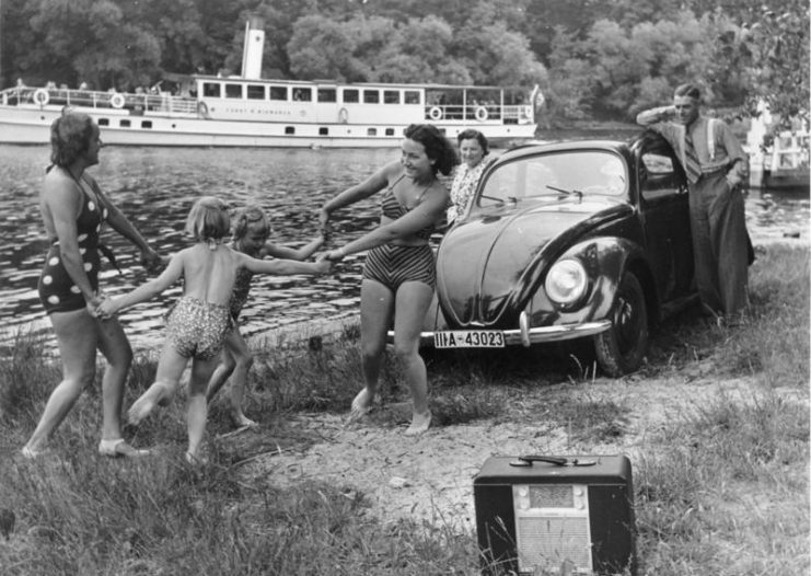 KdF Propaganda: “A family playing by a river with a KdF-Wagen and radio receiver”. CC BY-SA 3.0 de