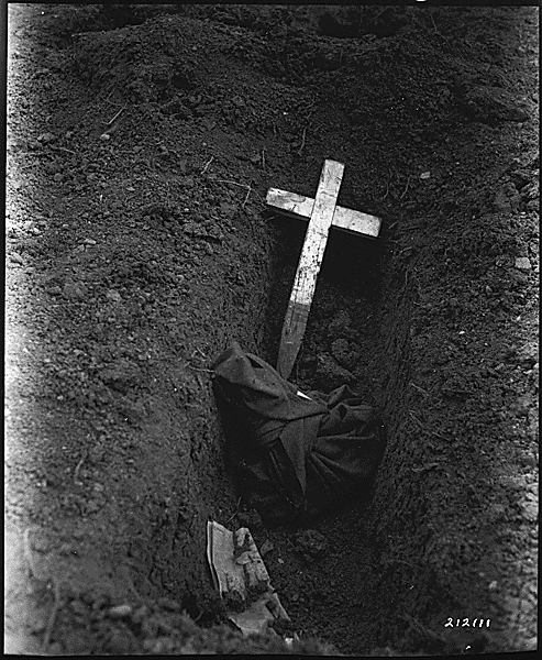 U.S. medical men are attempting to identify more than 100 American Prisoners of War captured at Bataan and Corregidor and burned alive by the Japanese at a Prisoner of War camp, Puerto Princesa, Palawan, Philippine Islands Picture shows charred remains being interred in grave.
