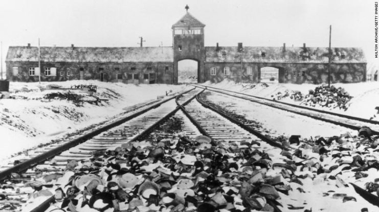 Snow-covered personal effects of those deported to the Auschwitz concentration camp litter the train tracks leading to the camp’s entrance, in an image from around 1945.