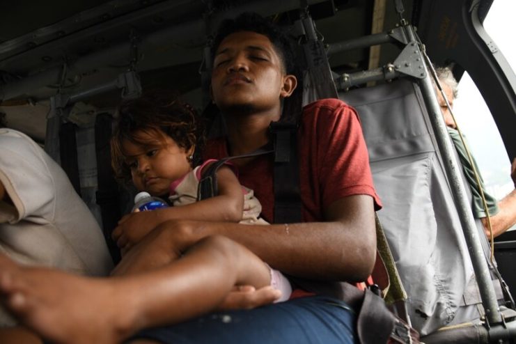 Honduran family members rest on a U.S. Army HH-60 Black Hawk helicopter after rescue from Hurricane Eta’s high floodwaters at San Pedro Sula, Honduras, Nov. 6, 2020. Image by US Air Force.