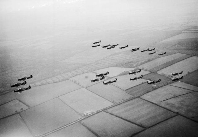 Hawker Hurricanes of No 1 Squadron, Royal Air Force, based at Wittering, Cambridgeshire, followed by a similar formation of Supermarine Spitfires of No 266 Squadron, during a flying display for aircraft factory workers, October 1940. [© IWM (CH 1561)]