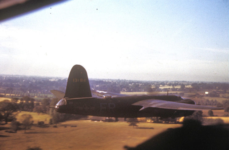 A B-26 Marauder (ER-F, serial number 41-31814) nicknamed Bag O Bolts of the 322nd Bomb Group from Andrews Field flies low over countryside.