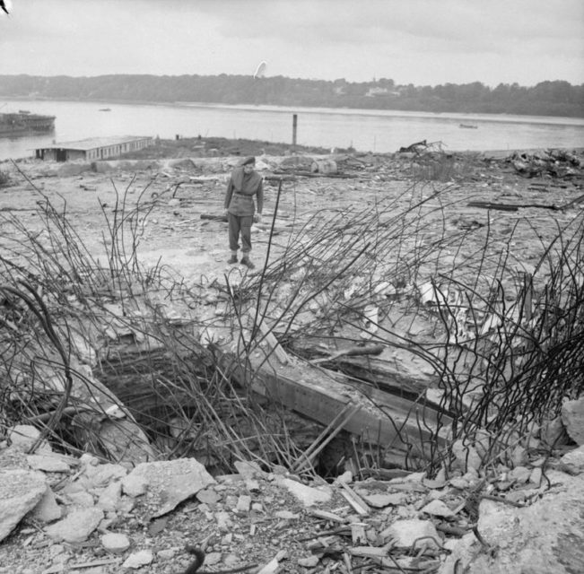 A British soldier from 224 Field Company, Royal Engineers, examines a hole made by a 12,000 lb bomb in the 11 foot thick concrete roof of the German submarine pens pens at Hamburg.