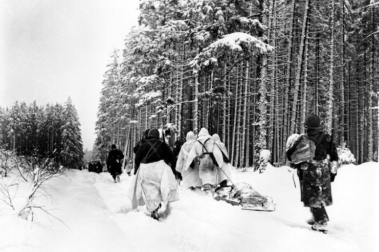 American troops drag a heavily loaded ammunition sled through the snow, as they move for an attack on Herresbach.