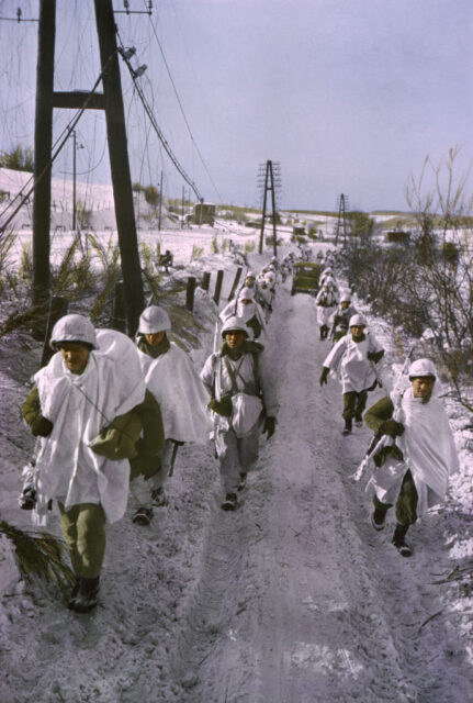 First US Army troops walking along a road during the Battle of the Bulge