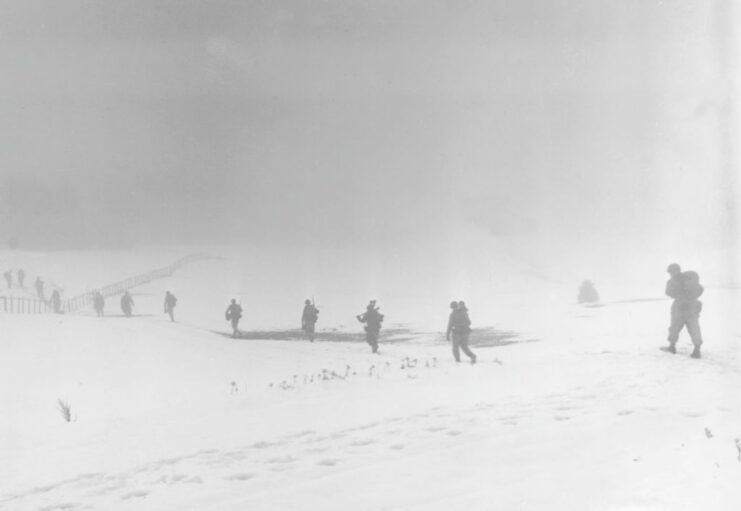 Soldiers walking through a snowy field during the Battle of the Bulge