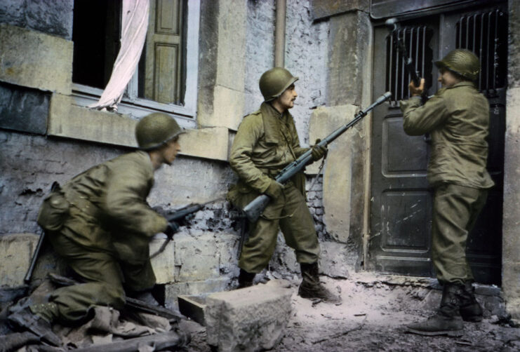 Three US infantrymen standing outside a house