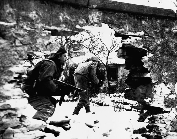 Two soldiers walking through the snow during the Battle of the Bulge