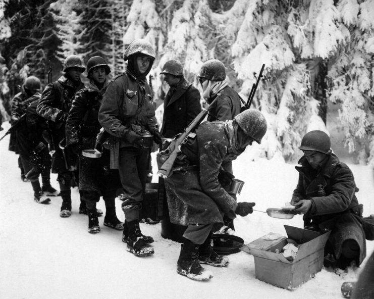 Chow is served to American infantrymen of the 347th Infantry Regiment on their way to La Roche, Belgium, 13 January 1945.
