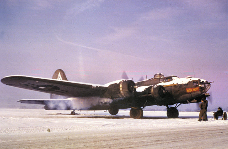Ground personnel watch a B-17 Flying Fortress nicknamed Ragin’ Red II of the 379th Bomb Group start up in snow at Bassingbourn, January 1945.