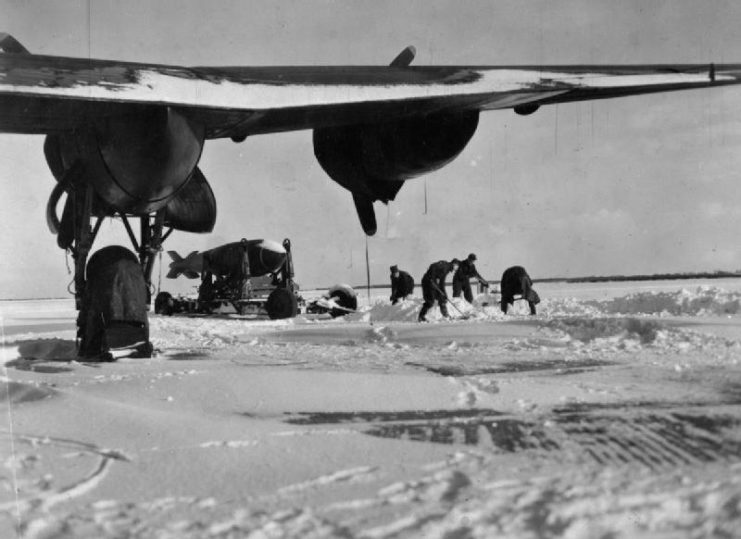 Groundcrew of No. 9 Squadron RAF, clearing snow in front of a trailer bearing a 12,000 lb ‘Tallboy’ deep-penetration bomb, at Bardney, Lincolnshire, in the winter of 1944 – 1945.