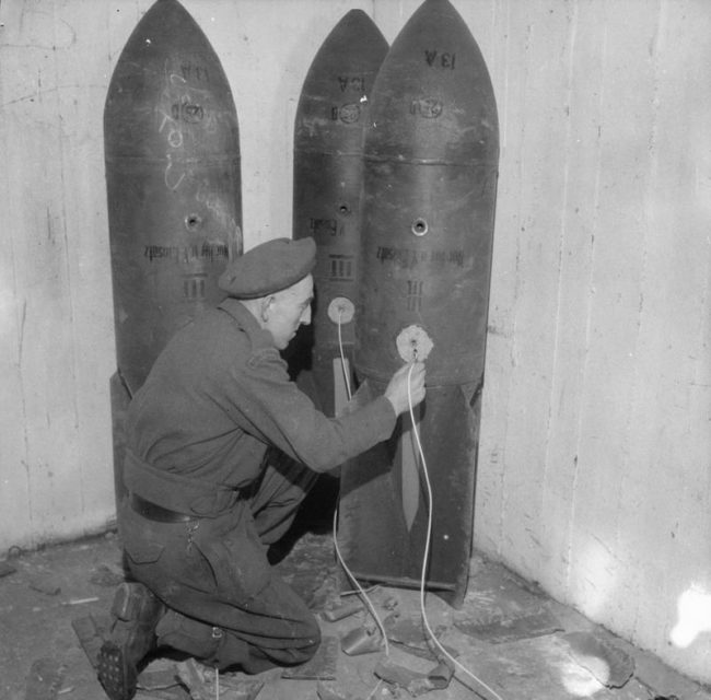 In preparation for the demolition of the U-Boat pens at Hamburg, Sapper Stidson from the Royal Engineers connects a group of German bombs with Cordtex-instantaneous detonation fuse.
