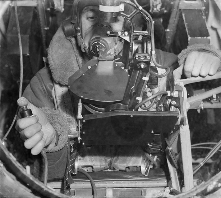 Flight Lieutenant P Walmsley, the bomb-aimer on board an Avro Lancaster B Mark III of No. 619 Squadron RAF, operating the bombsight at his position in the nose of the aircraft, at Coningsby, Lincolnshire.
