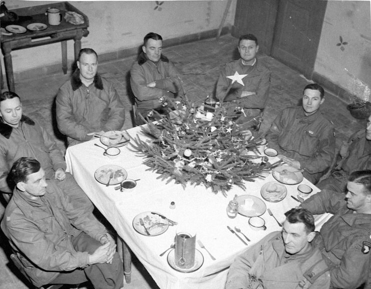 Paratroopers with the 101st Airborne Division sitting around a table topped with a Christmas tree
