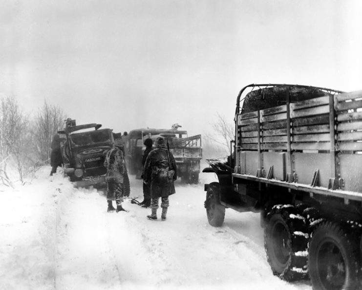 Snow and Ice make the going tough for U.S. Army vehicles on a road in Belgium. The snowstorm was responsible for the gasoline truck, at left, skidding off the road, with a traffic jam as the result.