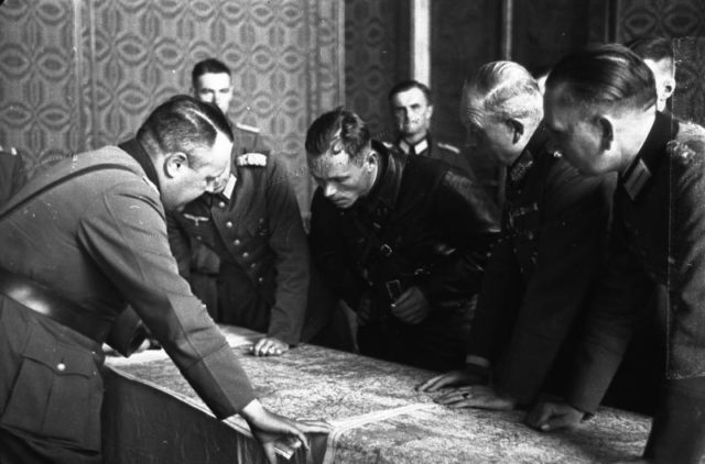 Soviet and German officers at the demarcation line examine a map.