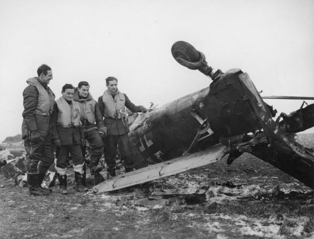 Spitfire pilots pose beside the wreckage of a Junkers Ju 87 Stuka, which they shot down as it was attacking a Channel convoy, 1940. [© IWM (CH 2064)]