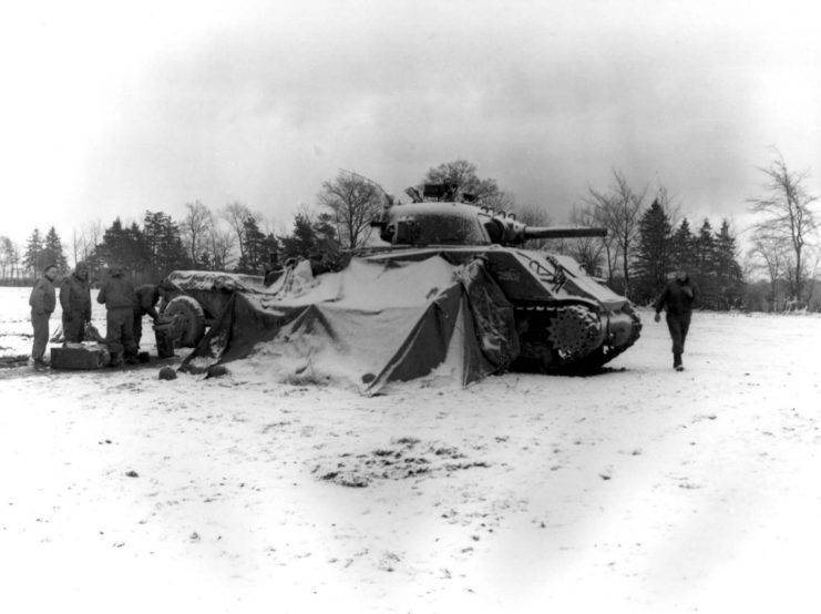 Tankmen of the U.S. First Army gather around a fire on the snow-covered ground near Eupen, Belgium, opening their Christmas packages December 30 1944.