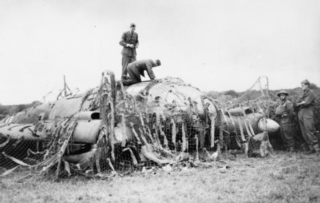 RAF personnel inspecting Heinkel He 111P (coded G1+FA) of Stab/KG 55 which was brought down at Hipley in Hampshire, 12 July 1940. It has been camouflaged to prevent the Luftwaffe attempting to destroy the remains. The bomber was shot down by ‘B’ Flight of No. 43 Squadron over Southampton Water.