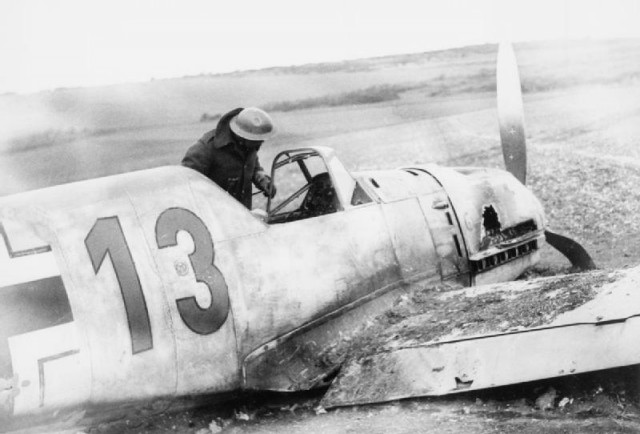 A soldier peers into the cockpit of a downed Messerschmitt Bf 109E. This is probably Bf 109E-1 (W.Nr. 3576) ‘Red 13’ of 7./JG 54, flown by Uffz. Zimmermann, which crashed near Lydd in Kent on 27 October 1940.