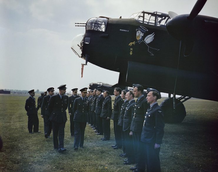 The King inspects ground crewmen lined up beneath the nose of Avro Lancaster B Mark I, ED989, DX-F, ‘Frederick III’.