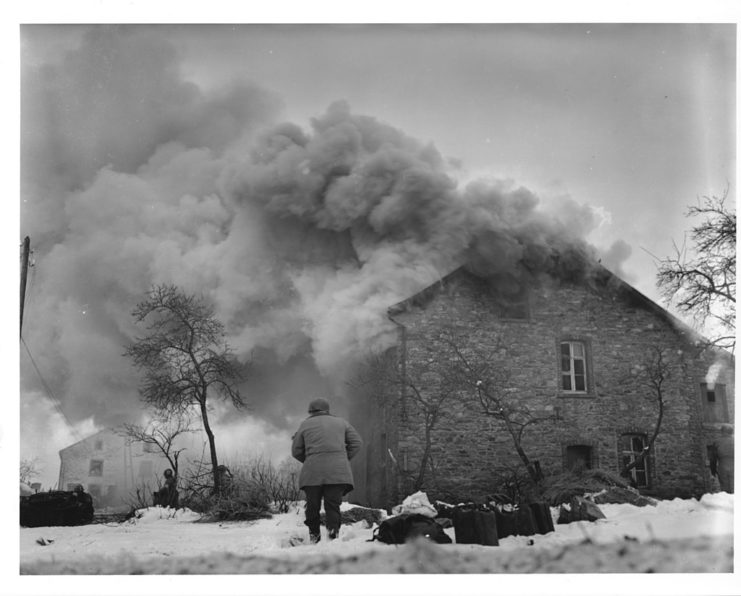 This burning home near Lmore, Belgium, drew a heavy barrage of enemy shellfire which wounded a Signal Corps photographer. Janurary 16 1945