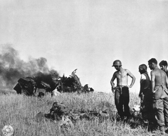 US soldiers in the vicinity of Gela. in the background destroyed German aircraft. 12 July 1943. [U.S. Army Signal Corps]