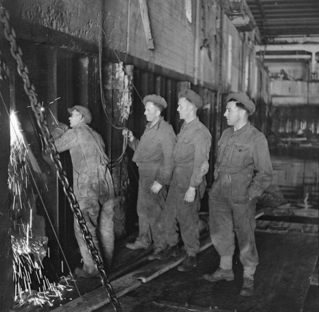 Working from rafts on the water, sappers of the Royal Engineers cut through steel girders of the Hamburg U-Boat pens to make spaces to house the explosive charges needed to demolish the pens.