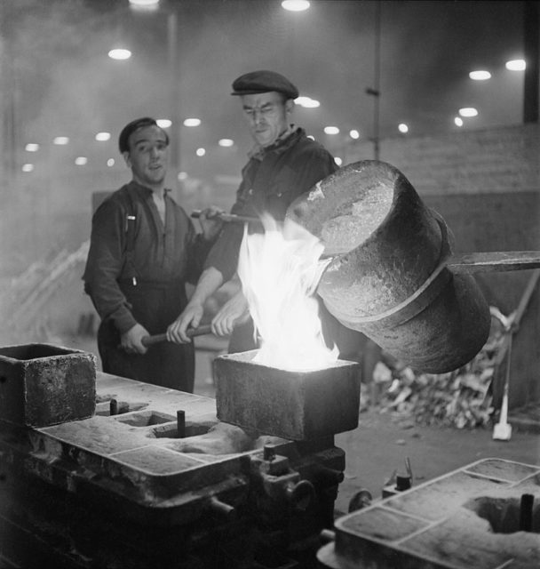 2 cwt of molten aluminium is emptied into a Merlin cylinder head mould by workers in an operation known as the ‘two-handed pour’.