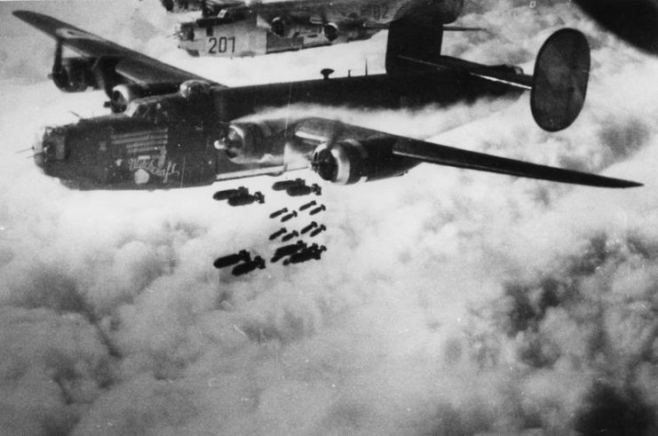 A B-24 Liberator (Q2-M_, serial number 42-52534) nicknamed Witchcraft of the 467th Bomb Group releases bombs over the target.