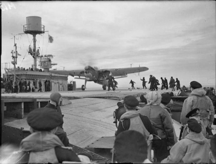 A Fairey Barracuda of 827 Squadron, Fleet Air Arm returns to HMS FURIOUS watched by other pilots who had returned after taking part in the operations.