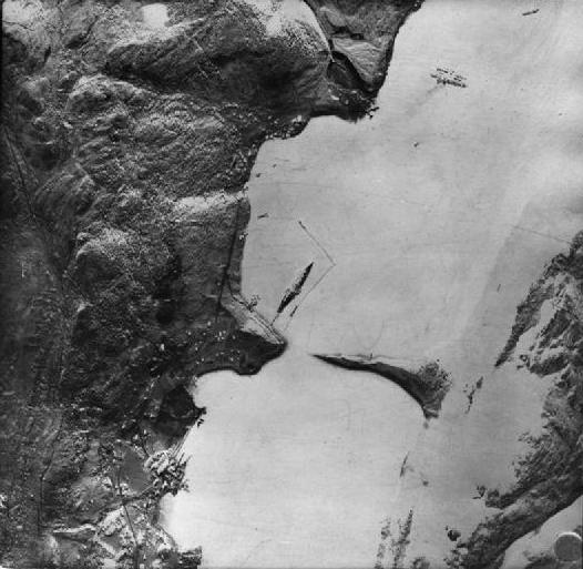 An aerial photograph of Alten Fjord showing the German battleship Tirpitz at her anchorage where she was attacked and damaged by British midget submarines. Note the L shaped torpedo net.