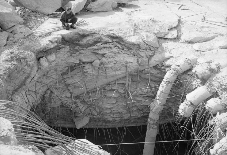 An RAF officer inspects the hole left by a Grand Slam in the reinforced concrete roof of the Valentin submarine pens at Bremen, Germany.