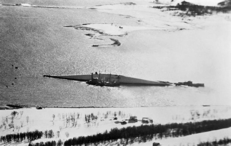 Low-level photographic-reconnaissance taken from a De Havilland Mosquito of No. 544 Squadron RAF, showing the capsized German battleship Tirpitz, lying in the Tromsø fjord near isle of Håkøya.