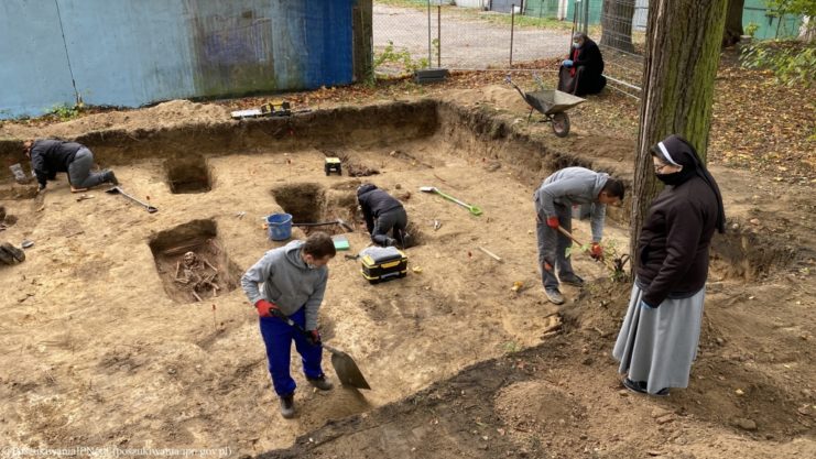 A nun watches over the site people work to discover and identify the remains