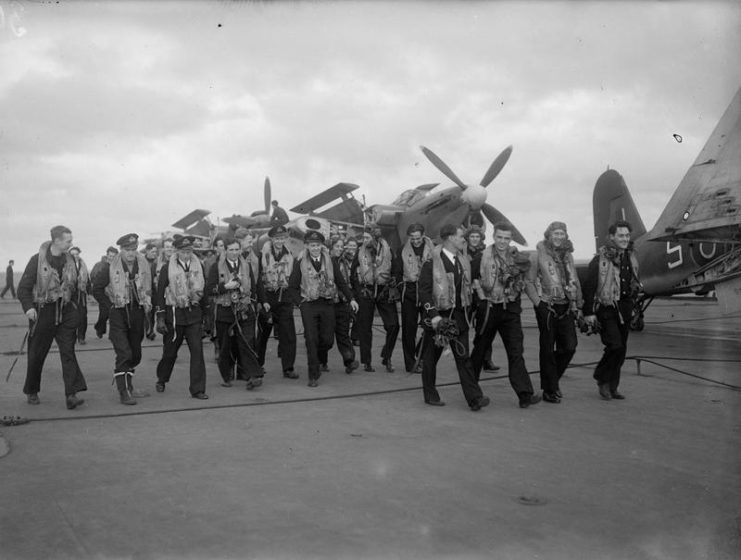 The crews of Baracuda and Corsair aircraft walking along the flight deck of an aircraft carrier following one of the raids conducted during Operation Goodwood