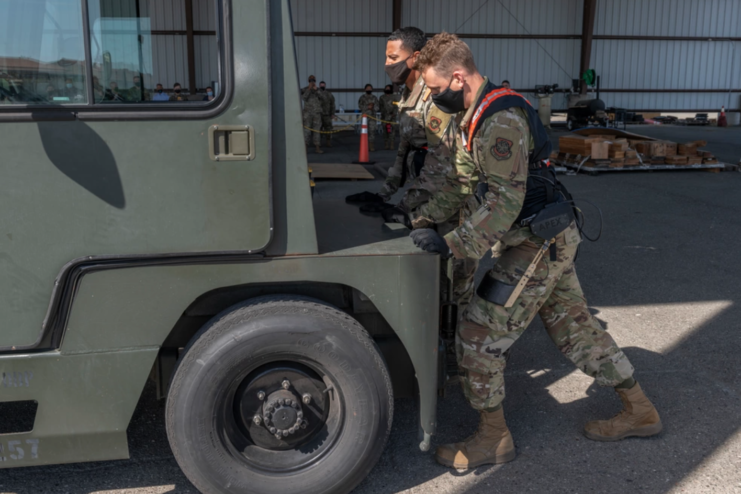 Airman 1st Class Xaviar Archangel and Airman 1st Class Kyle Sunderman pushing a military vehicle while wearing Aerial Porter Exoskeletons