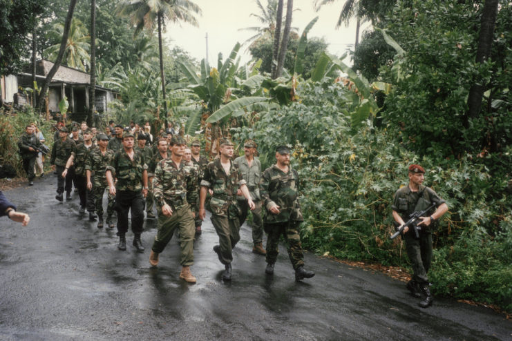 Soldiers walking down a rain-soaked road in Comoros