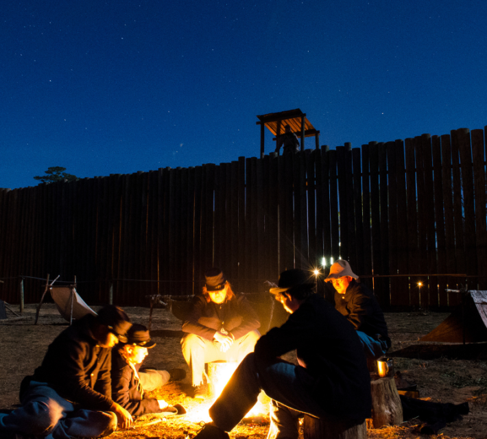 Volunteers reenact prisoners at Andersonville huddling around a fire.