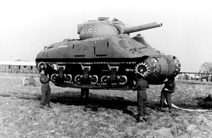 Four soldiers holding up an inflatable tank
