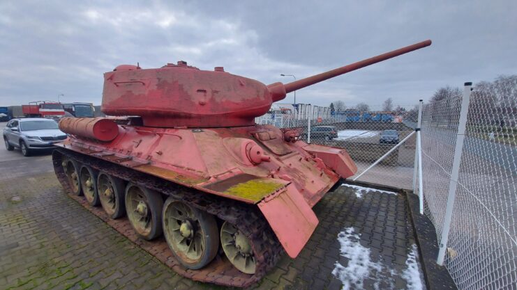 Pink T-34-85 parked behind a chain link fence