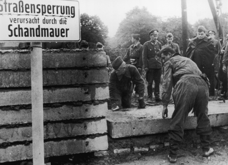 Soldaten bauen einen Teil der Berliner Mauer wieder auf.